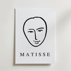 Minimal Matisse Poster by Bozetto har ett minimalistiskt svart linjeansikte på en vit bakgrund med fet "MATISSE" text, tryckt på premiumpapper med en matt finish för en elegant look.