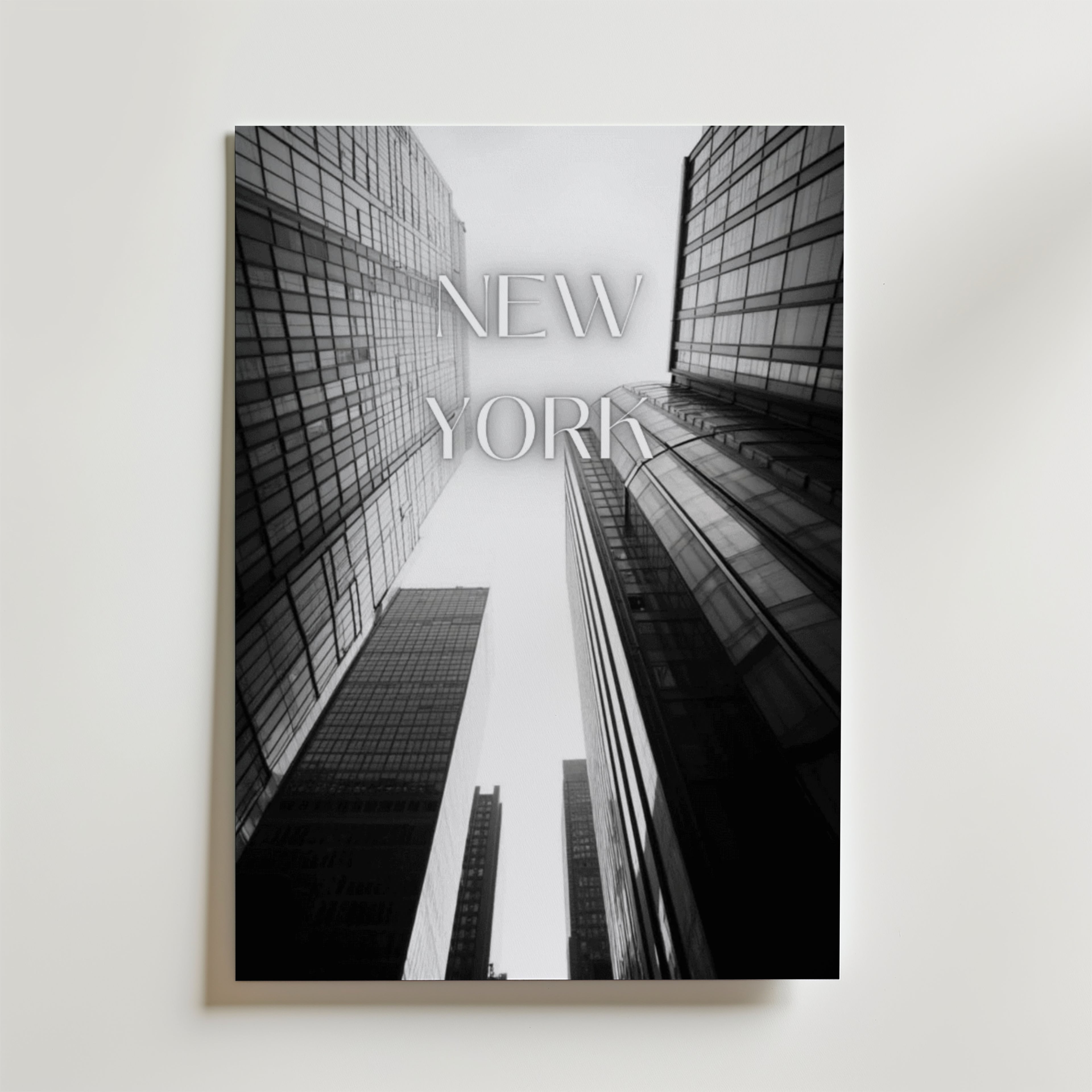 Bozetto New York Poster föreställer svartvita skyskrapor tagna från en låg vinkel med "NEW YORK" i transparenta bokstäver, tryckt på FSC-certifierat premiumpapper för en miljövänlig touch.