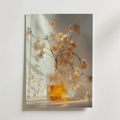 Bozettos affisch Glass vase with amber liquid föreställer en klar flaska med bärnstensfärgad vätska och vita blommor som kastar mjuka skuggor - ett elegant konstverk som är perfekt för alla moderna konstsamlingar.