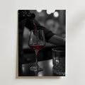 Bozetto Pouring Passion Wine Poster visar rött vin som hälls upp i ett glas på en mörk yta bredvid ett tomt glas, med mjukt suddiga bokeh-ljus som förstärker skönheten i vin i rörelse.