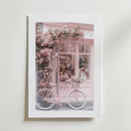 La Vie en Rose Poster by Bozetto föreställer en butikslokal i mjuka rosa toner, blommande blommor och en rosa vintage cykel, vilket skapar en romantisk pastell look med en elegant, lyxigt matt yta.