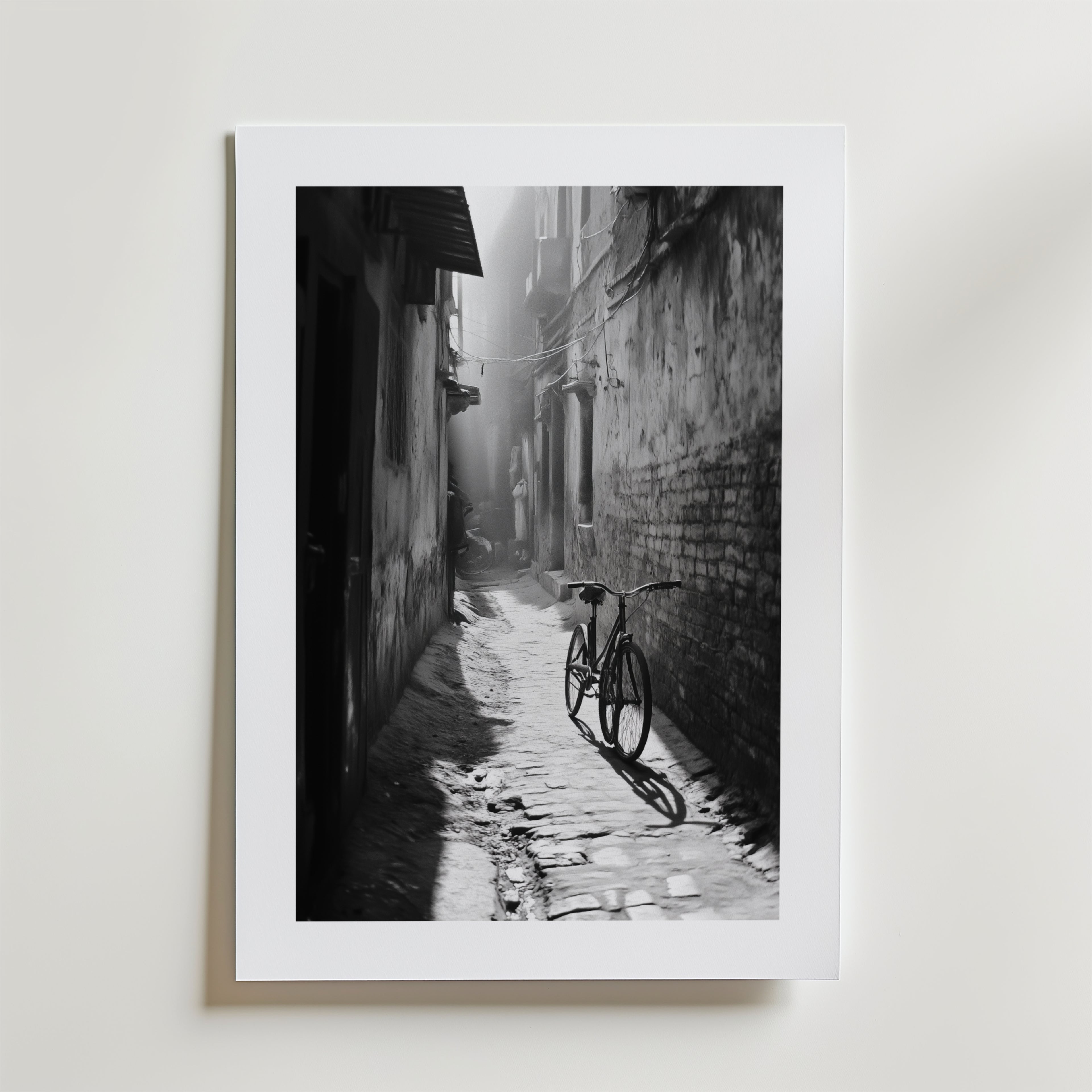 Quiet Echo Poster by Bozetto har ett svartvitt foto av en smal kullerstensgränd där solljuset kastar en cykels skugga genom dimman, tryckt på FSC-certifierat premiumpapper för en högkvalitativ finish.
