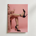 En person i rosa päls och glänsande svarta klackar sitter med champagne mot en rosa bakgrund - på Elegant Champgane Poster by Bozetto, tryckt på premiumpapper.