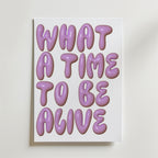What a Time Poster by Bozetto har en fet, glansig lila text som säger WHAT A TIME TO BE ALIVE i bubblande typografi på en vit bakgrund - en upplyftande poster som ger glädje till ditt hem.