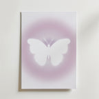 Bozetto's Soft Glow Butterfly Poster visar en vit fjäril i silhuett centrerad mot en ljus, minimalistisk bakgrund med drömskt rosa-lila sken.